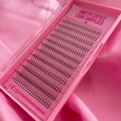 Black individual lash extensions in a clear tray with a pink background, perfect for eyelash extensions.