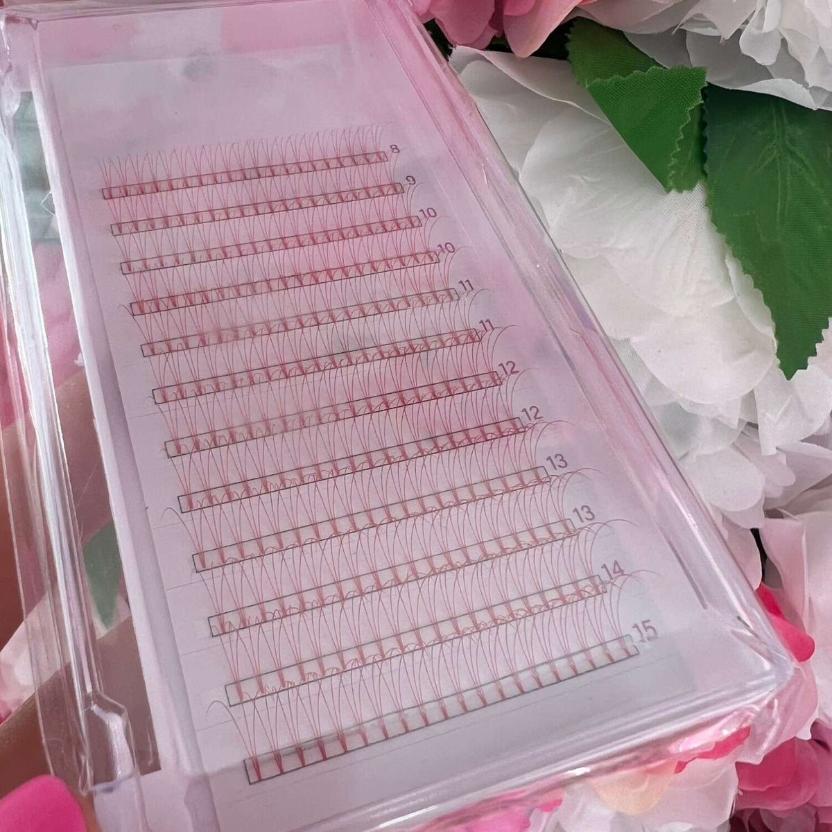 Pink lash extension tray with pre-fanned volume lashes in various lengths from 8mm to 15mm. A professional beauty tool.
