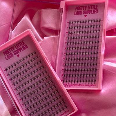 Pink eyelash extension trays with black lashes, showcasing various lengths and styles, inside a glossy pink case.