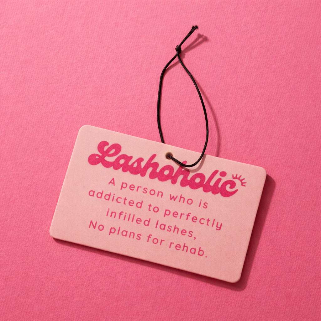 Pink "Lashaholic" car scent with black string, featuring a fun definition of lash addiction.