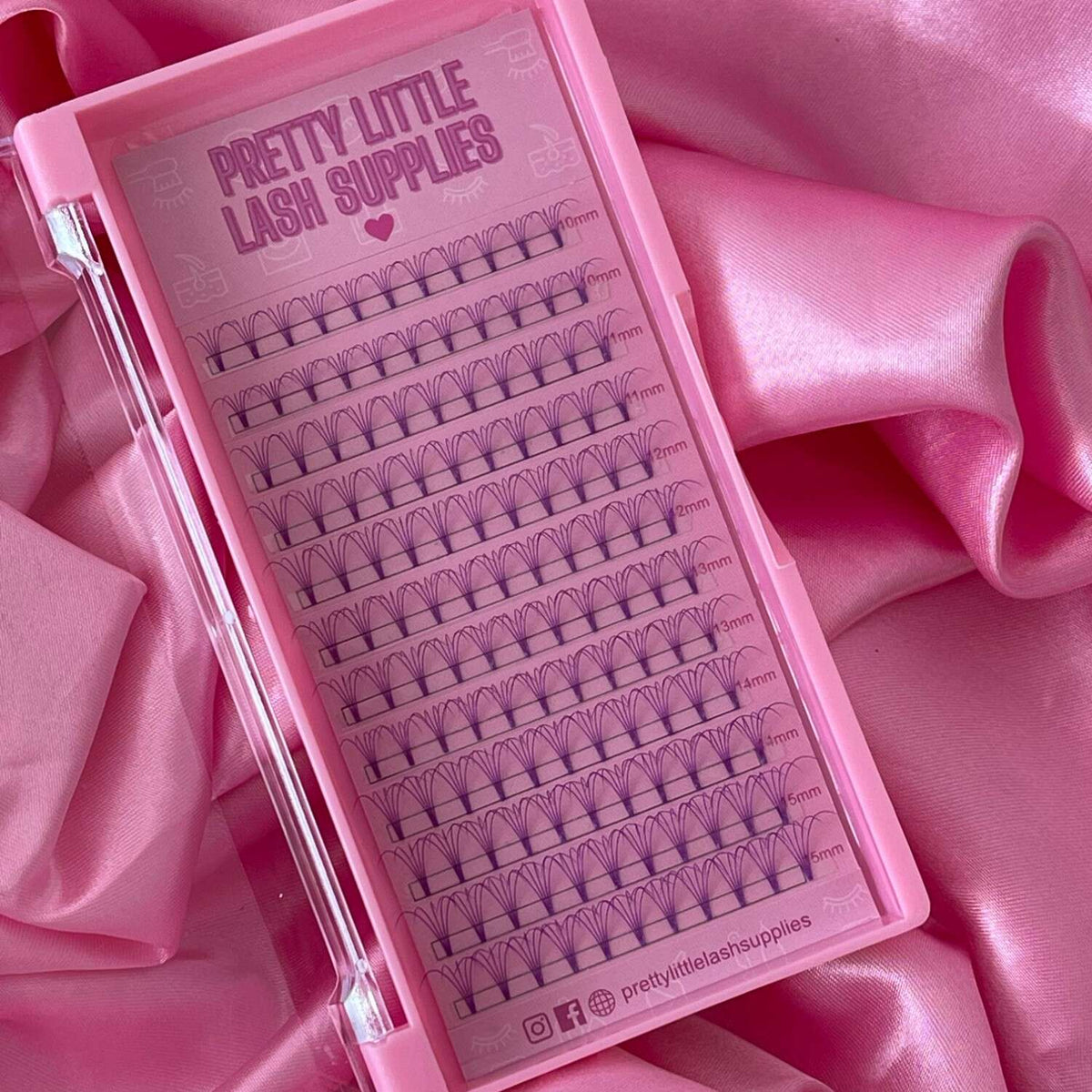 Pretty Little Lash Supplies pink lash tray with individual lashes in various lengths, set against soft pink satin fabric.
