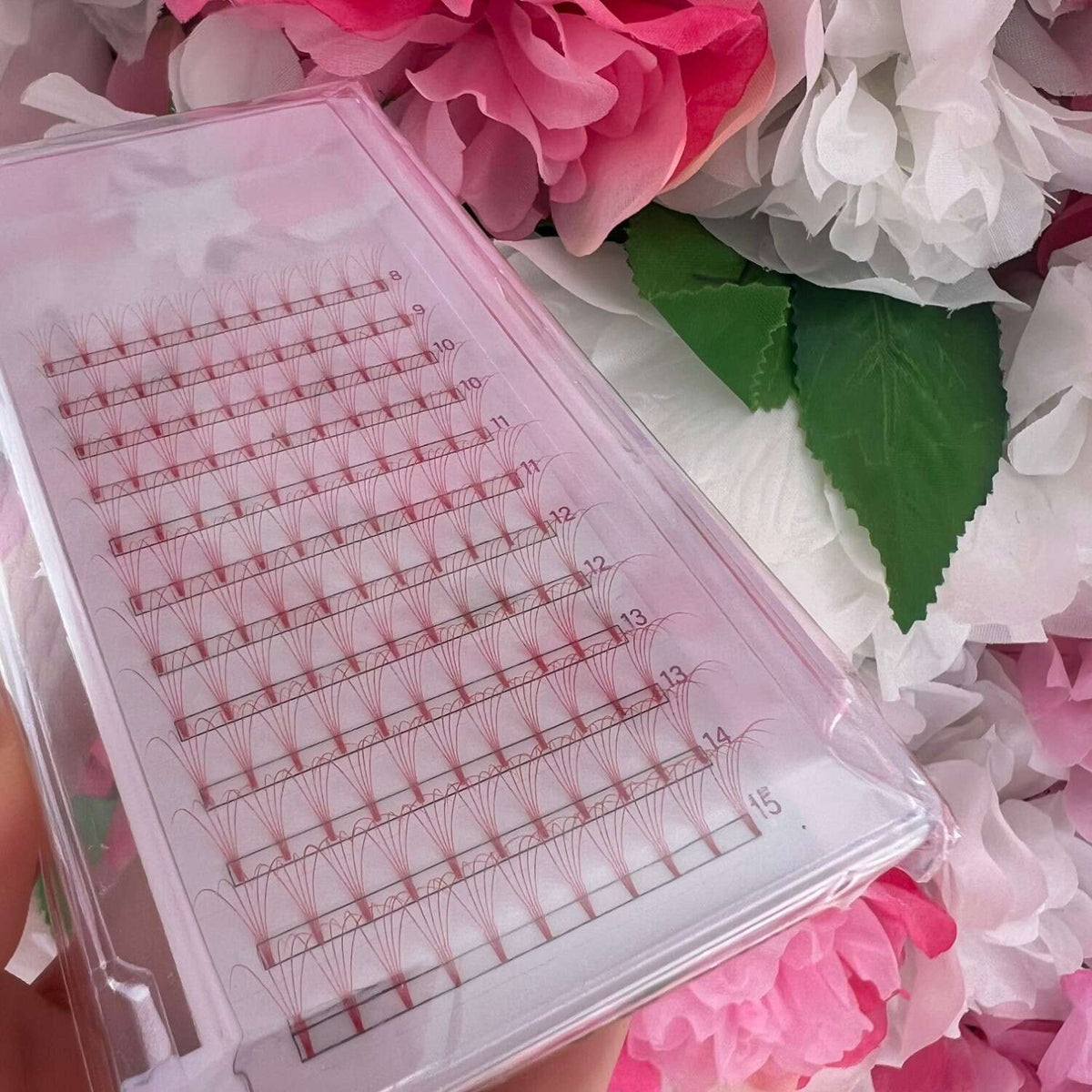 Lightweight pink eyelash extension trays with varying lengths, perfect for volume lashes. Ideal for beauty professionals.