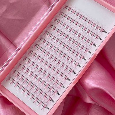 Pink 0.07mm volume lash extensions in a clear tray, featuring varying lengths from 10mm to 15mm on a soft satin backdrop.
