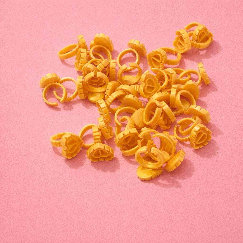 Yellow heart-shaped hair clip rings on a pink background, perfect for styling and securing hair.