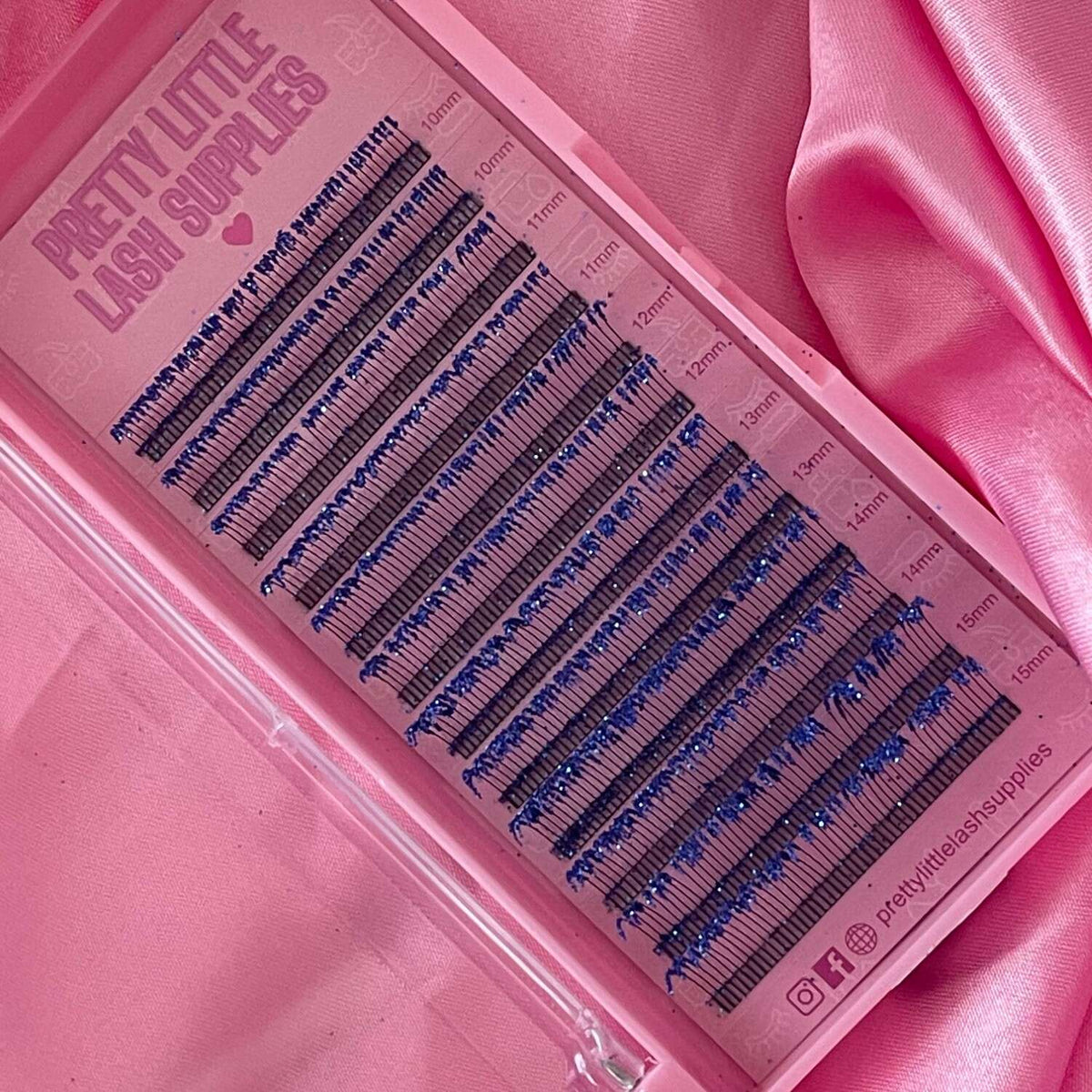 Blue silk eyelash extensions on a pink lash tray, featuring various lengths in a stylish presentation.