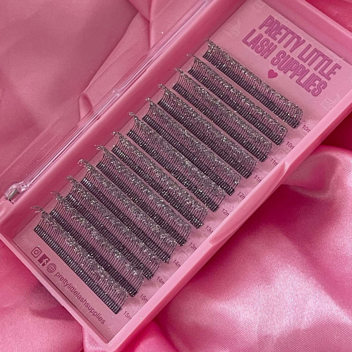 Purple synthetic eyelash extensions in a clear tray, featuring varying lengths for versatile styling options.