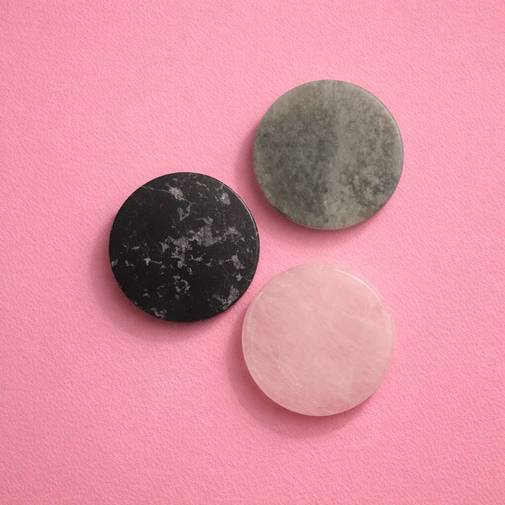 Set of three round gemstone lash trays in black, green, and pink on a pink background.