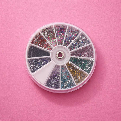 Colorful assorted rhinestones wheel, featuring multicolored acrylic gems in various sizes on a pink background.