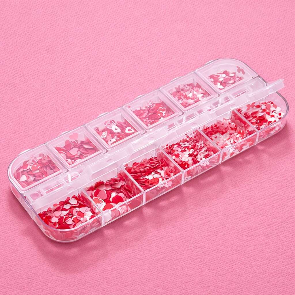 Clear plastic storage box filled with vibrant red and pink confetti shapes for arts and crafts.