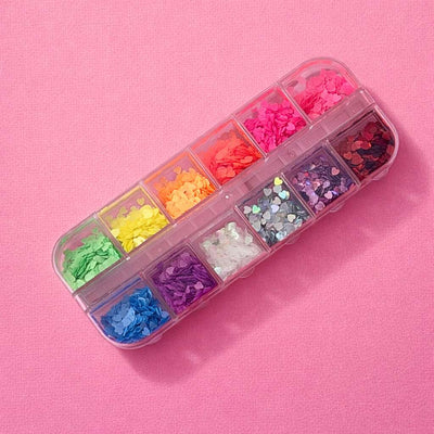 Colorful heart-shaped nail art glitter in a clear organizer, featuring pink, orange, yellow, green, and more.