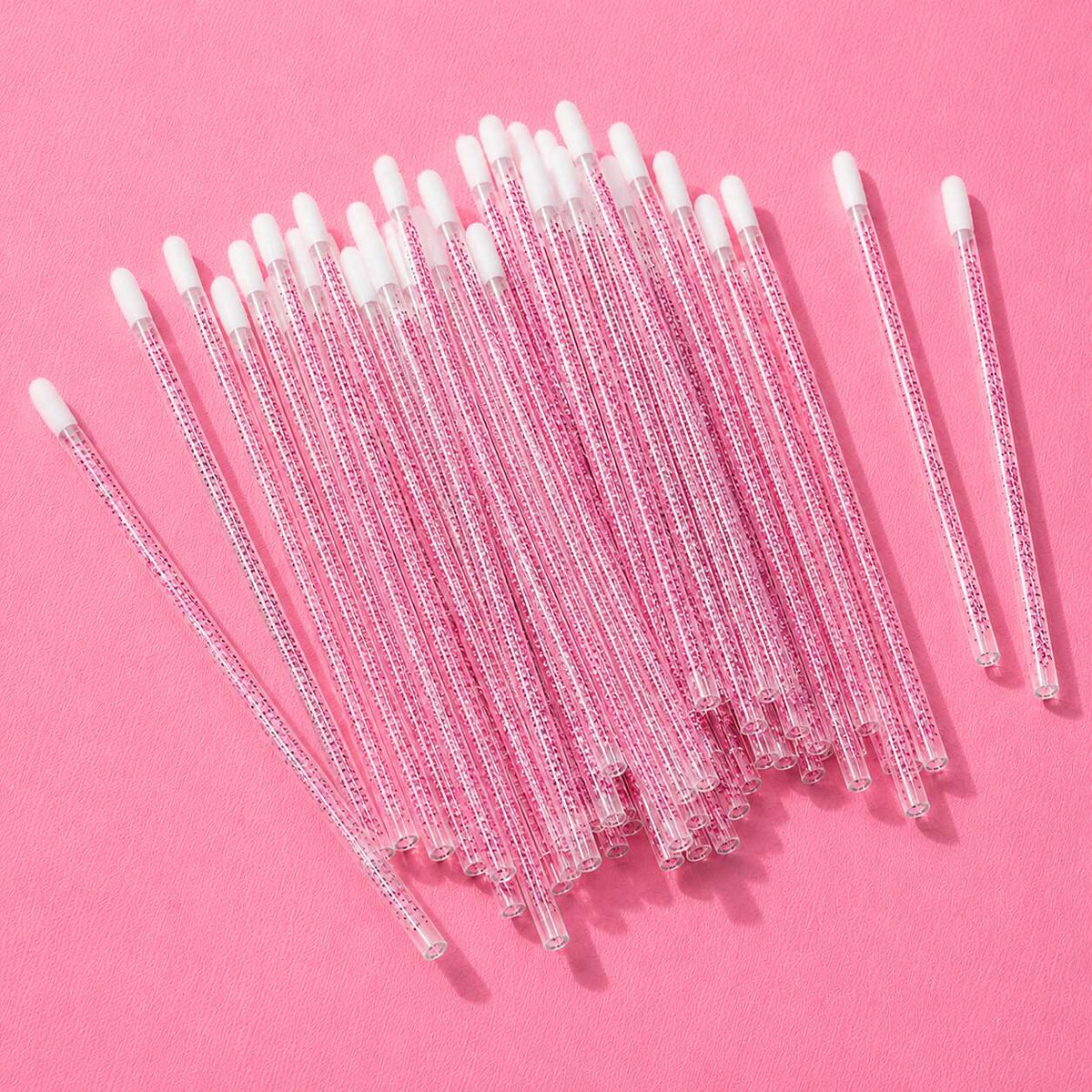 Pack of 50 clear pink glass stir sticks with white silicone tips, perfect for cocktails and coffee.