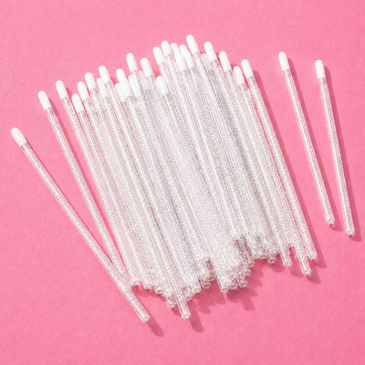 Clear glass stir sticks with white tips, perfect for cocktails and beverages, set against a pink background.