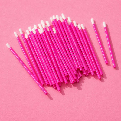 Bright pink disposable cosmetic swabs with pointed tips on a pink background, perfect for makeup application and touch-ups.