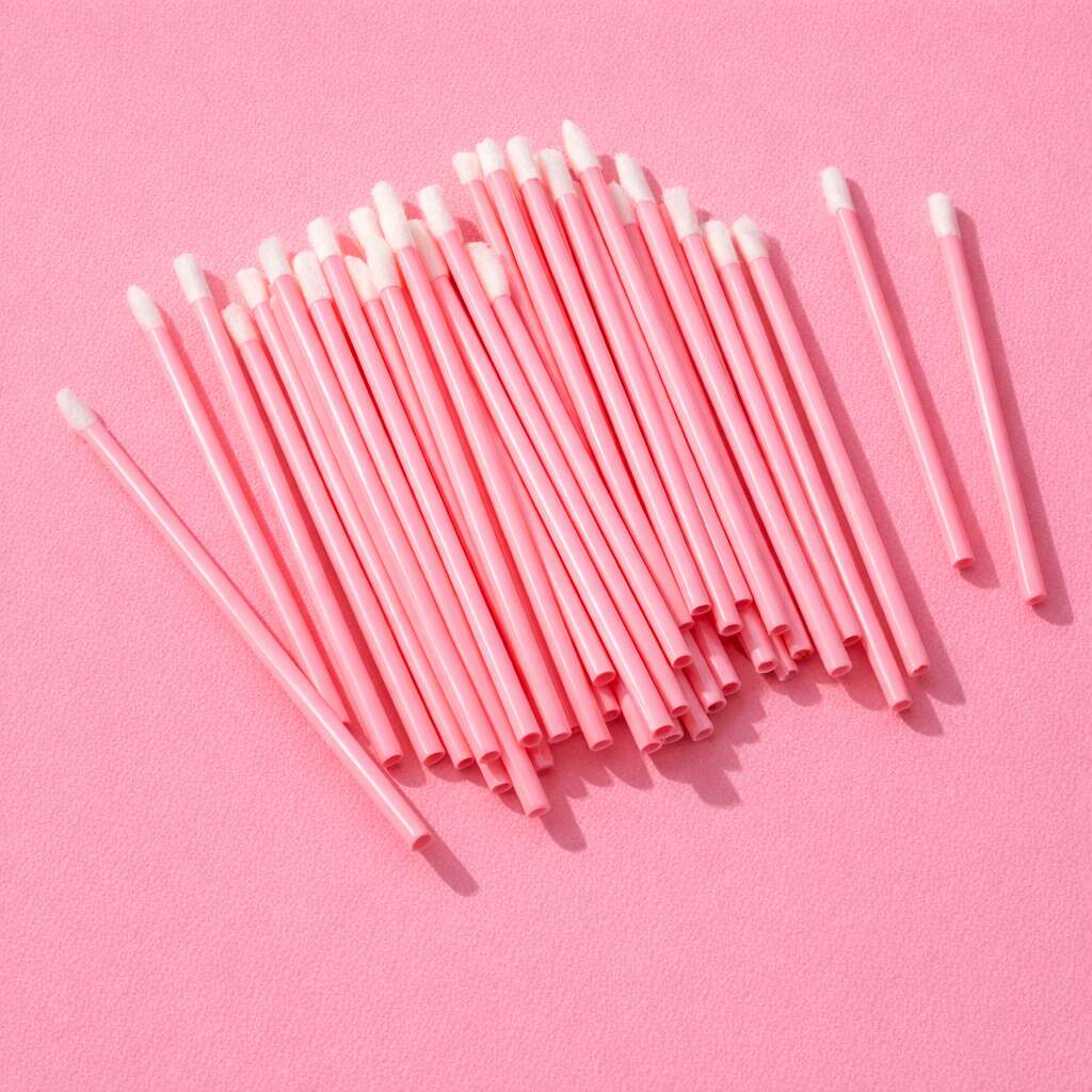 Pink disposable cotton swabs with soft tips, perfect for makeup application and touch-ups, on a pink background.