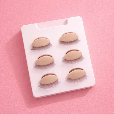 Six pairs of handcrafted false eyelashes on a pale pink holder, featuring natural fluttery styles.