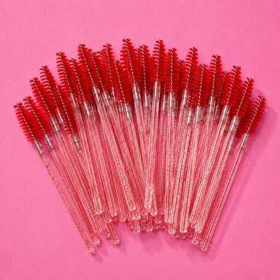 Set of 25 clear handle mascara wands with bright red bristles on a pink background. Perfect for beauty applications.