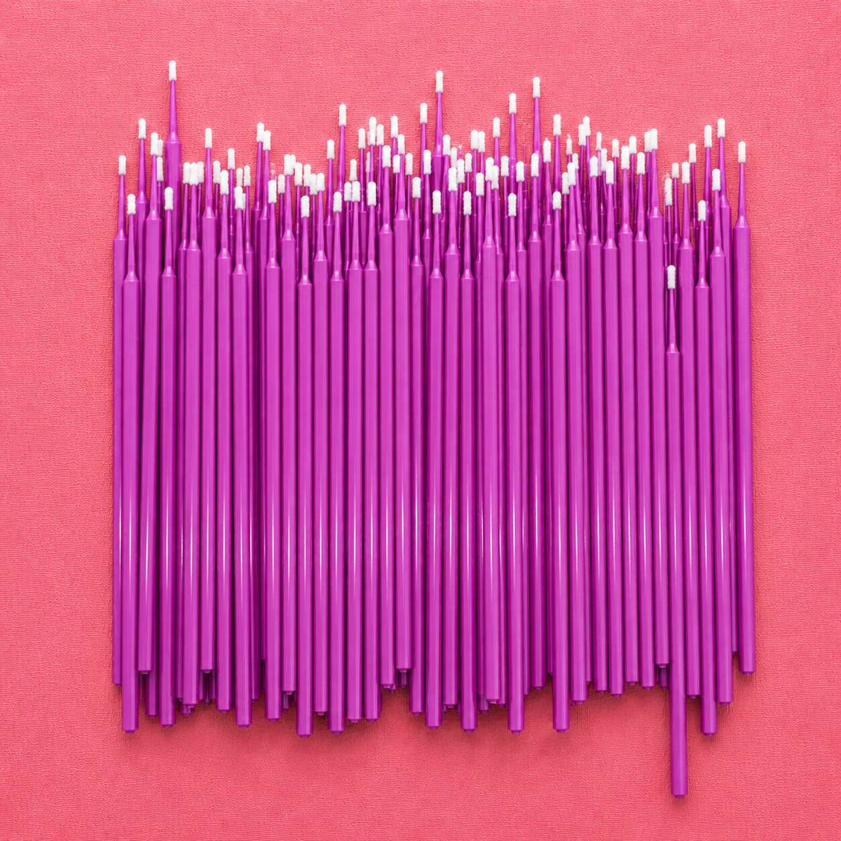Vibrant purple craft sticks arranged neatly on a pink background, perfect for DIY projects and creative activities.