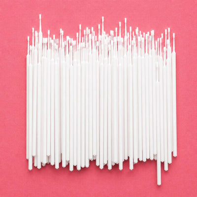 Set of 100 white, thin wax candle wicks on a pink background, perfect for DIY candle making projects.