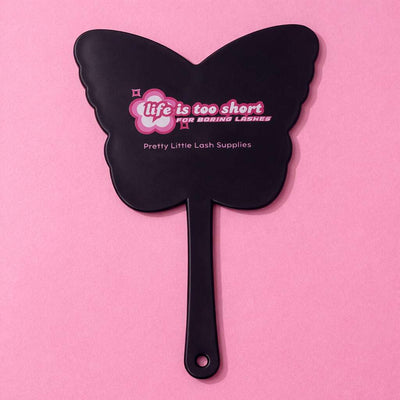 Black butterfly-shaped cosmetic mirror with pink text, "Life is too short for boring lashes," by Pretty Little Lash Supplies.