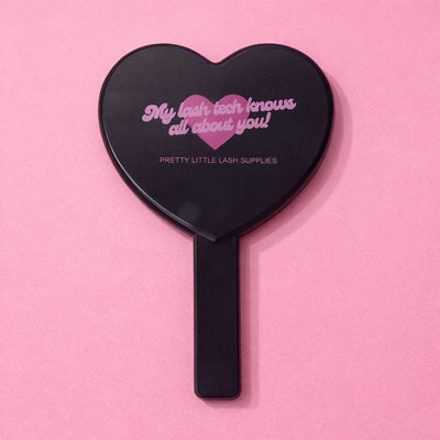 Heart-shaped black cosmetic mirror with pink text, perfect for lash technicians. Ideal for beauty enthusiasts.