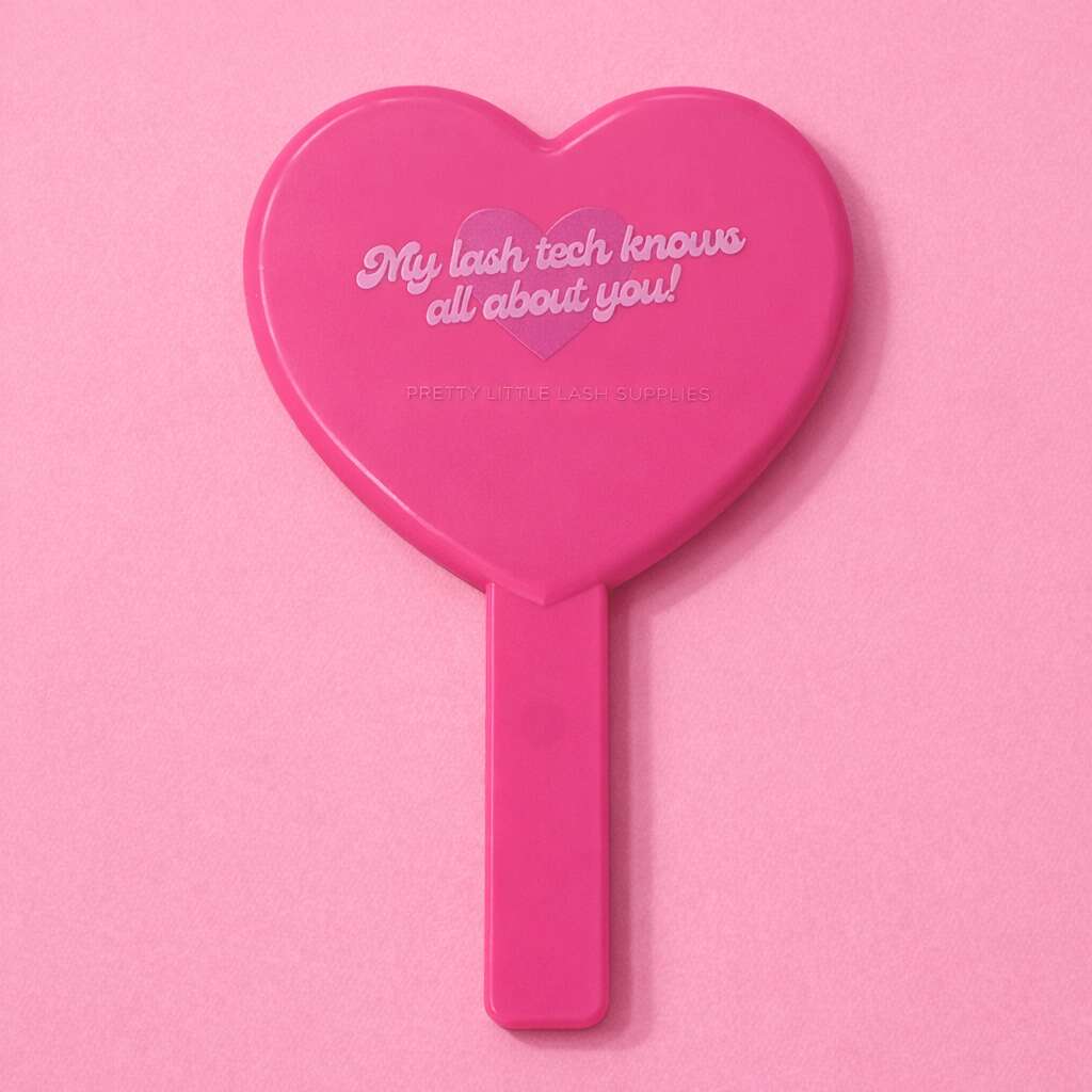 Pink heart-shaped cosmetic mirror with text "My lash tech knows all about you!" perfect for beauty professionals.