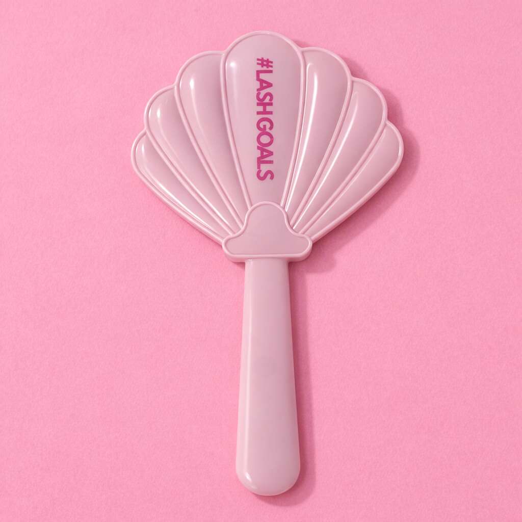 Pink shell-shaped cosmetic mirror with "#LASHGOALS" text for makeup lovers. Perfect for quick drying and styling lashes.