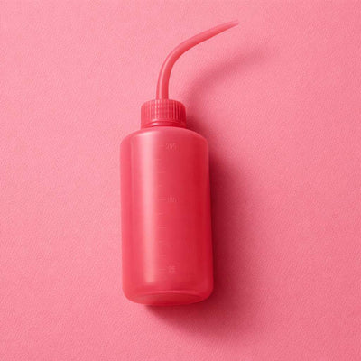 Bright pink plastic squeeze bottle with a long spout, ideal for precise pouring in kitchens or crafts.