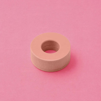 Pink adhesive tape roll on a soft pink background, featuring a textured finish and a central core.