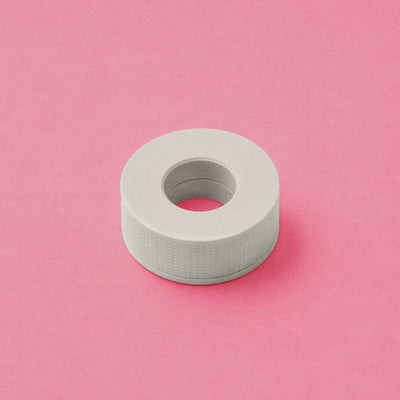White textured washi tape roll on a pink background, perfect for crafting and decorating.