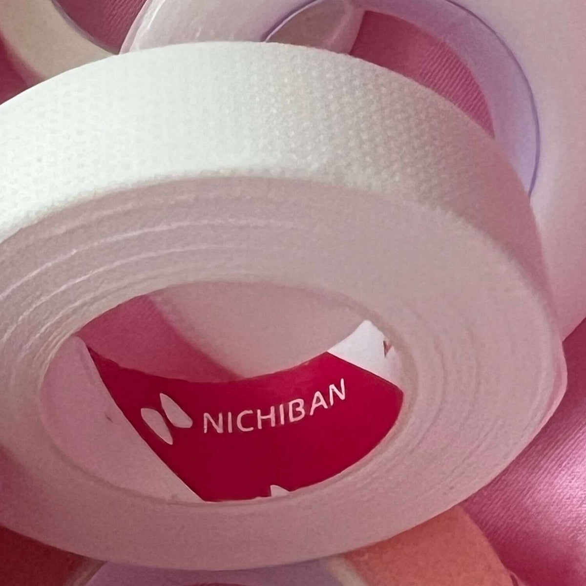 White Nichiban adhesive tape roll, textured surface, perfect for crafting and office use.