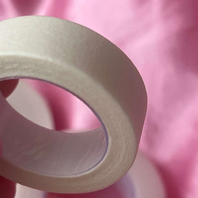 White paper masking tape roll on soft pink background, ideal for crafting and painting tasks.