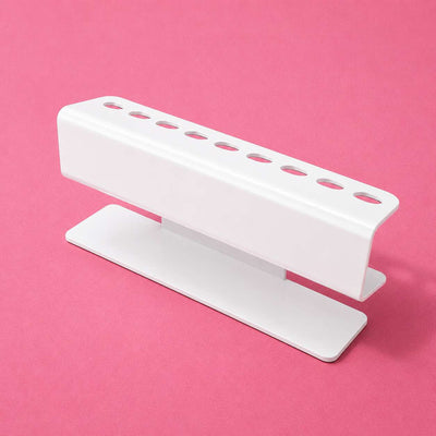 White metal pen holder with multiple slots on a pink background, showcasing a modern, minimalist design.