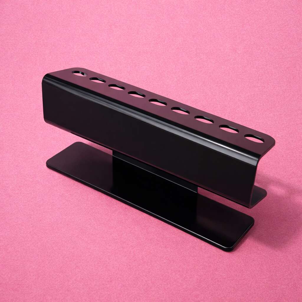 Sleek black metal pen holder with eight holes, minimalist design, ideal for modern office decor on pink background.