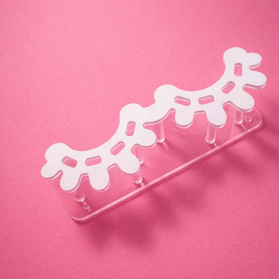 White acrylic hair accessory organizer on pink background, featuring a playful coral design with 5 pegs.