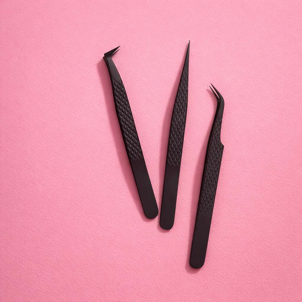 Set of three black precision tweezers with textured grip, ideal for grooming and crafting on pink background.