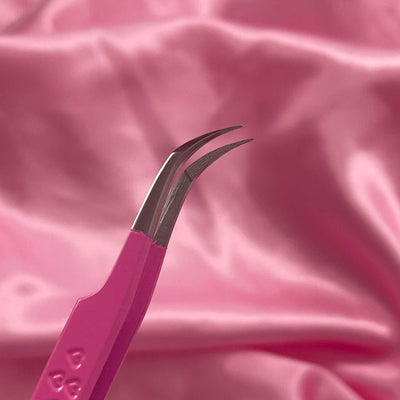 Pink stainless steel tweezers with curved tips, perfect for precision tasks against a soft pink satin background.