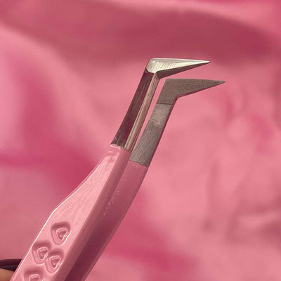 Pink stainless steel tweezers with angled tips for precise application against a soft pink background.