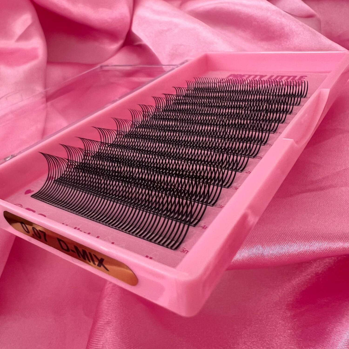 Mixed black eyelash extensions in a pink tray, perfect for a voluminous and natural look.